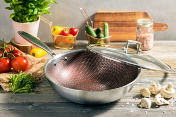 Patelnia typu WOK o średnicy 28 cm, wykonana ze stali nierdzewnej, z szklaną pokrywką i ergonomicznym uchwytem.